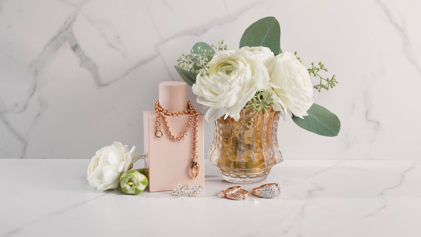 pretty rose gold jewelry with vase of flowers and perfume bottle