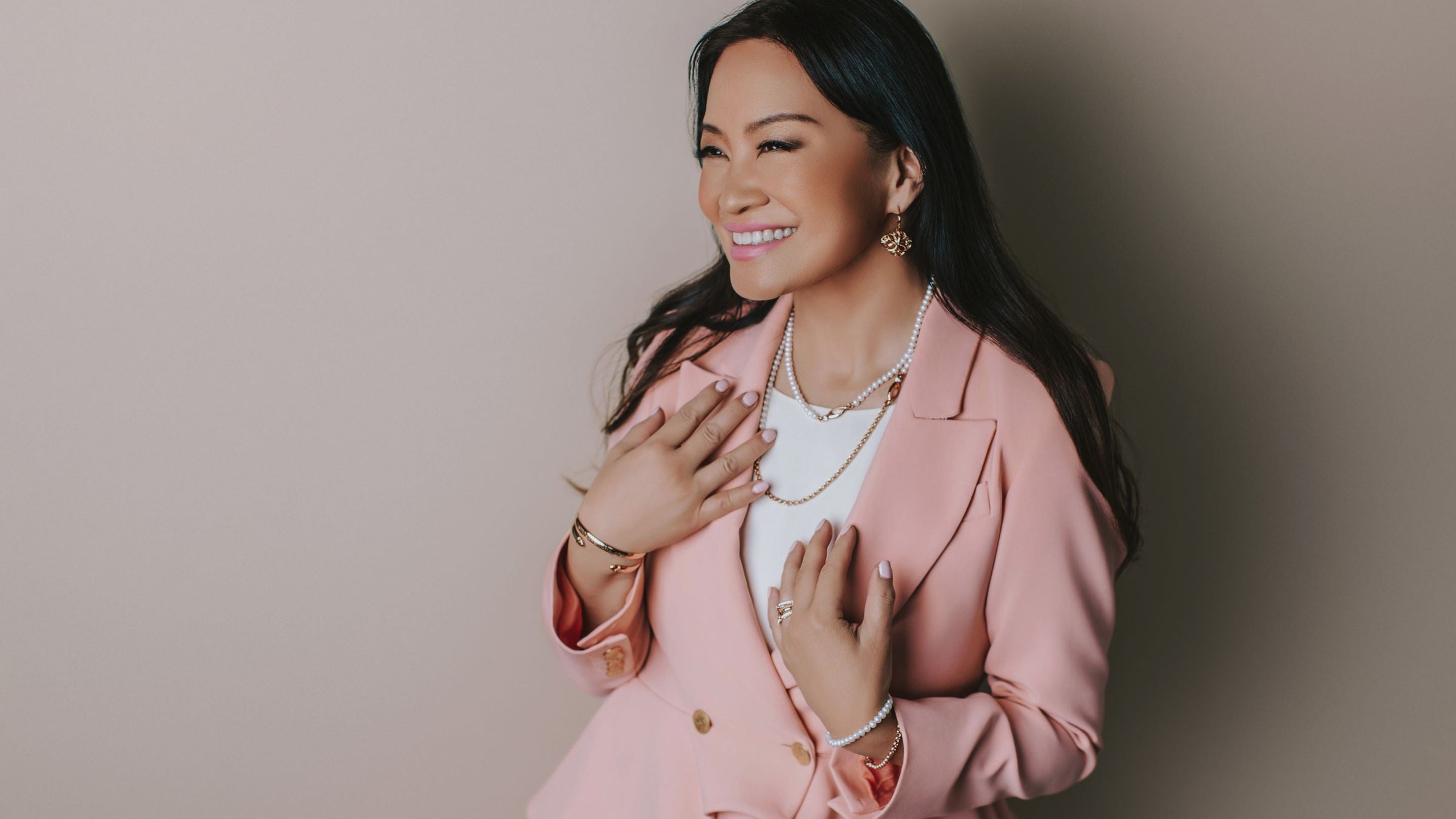 Lara Ertwine wears Rose Gold jewelry from REALM with white jacket