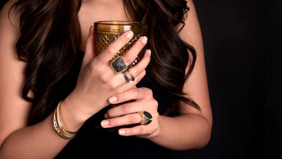 woman holding amber glass wearing dramatic gold and black cz jewelry from REALM