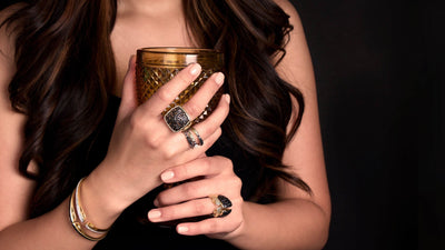 woman holding amber glass wearing dramatic gold and black cz jewelry from REALM