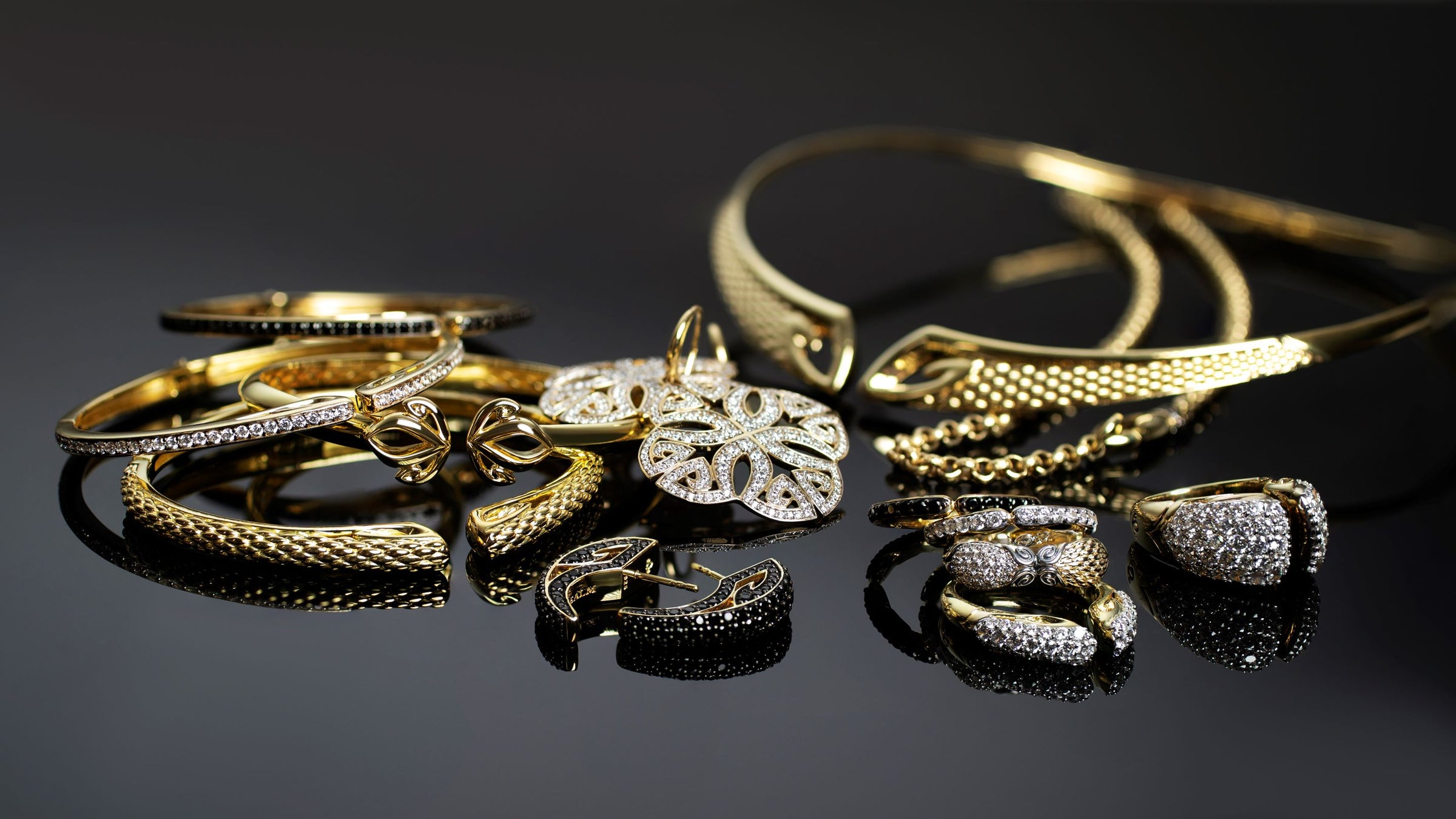 Luxurious array of gold and sparkly bracelets, earrings, rings, necklaces from REALM Fine + Fashion Jewelry