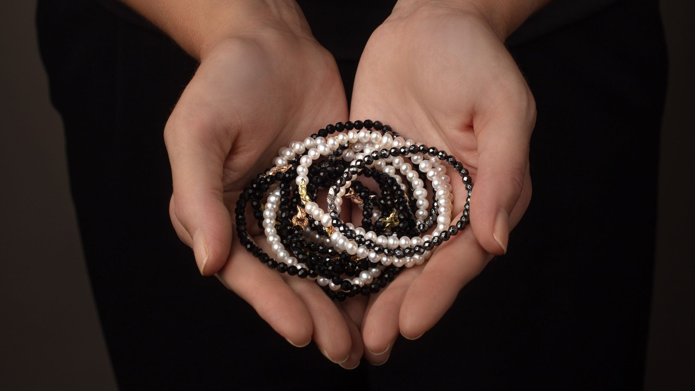 Woman's hands cradle REALM beaded Bond Bracelets in pearl, black agate and hematite