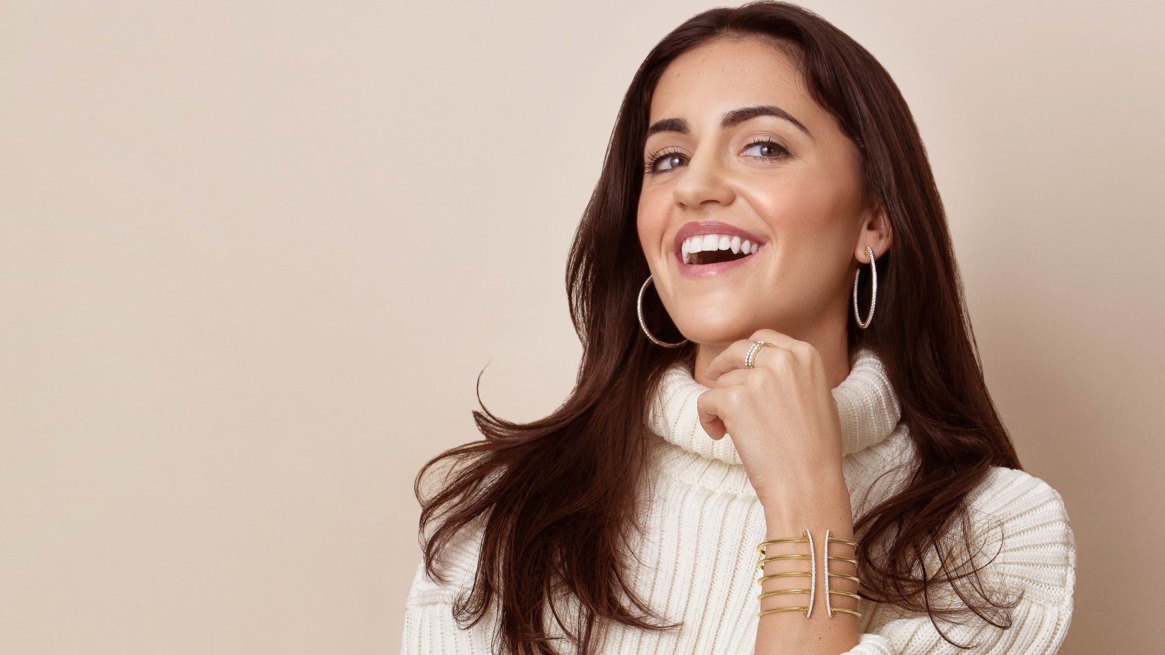Cozy chic holiday look - woman in cream sweater with dazzling earrings and cuff bracelet from REALM.