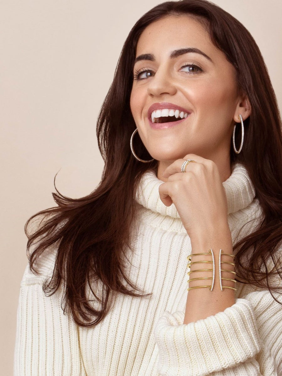 Cozy chic holiday look - woman in cream sweater with dazzling earrings and cuff bracelet from REALM.