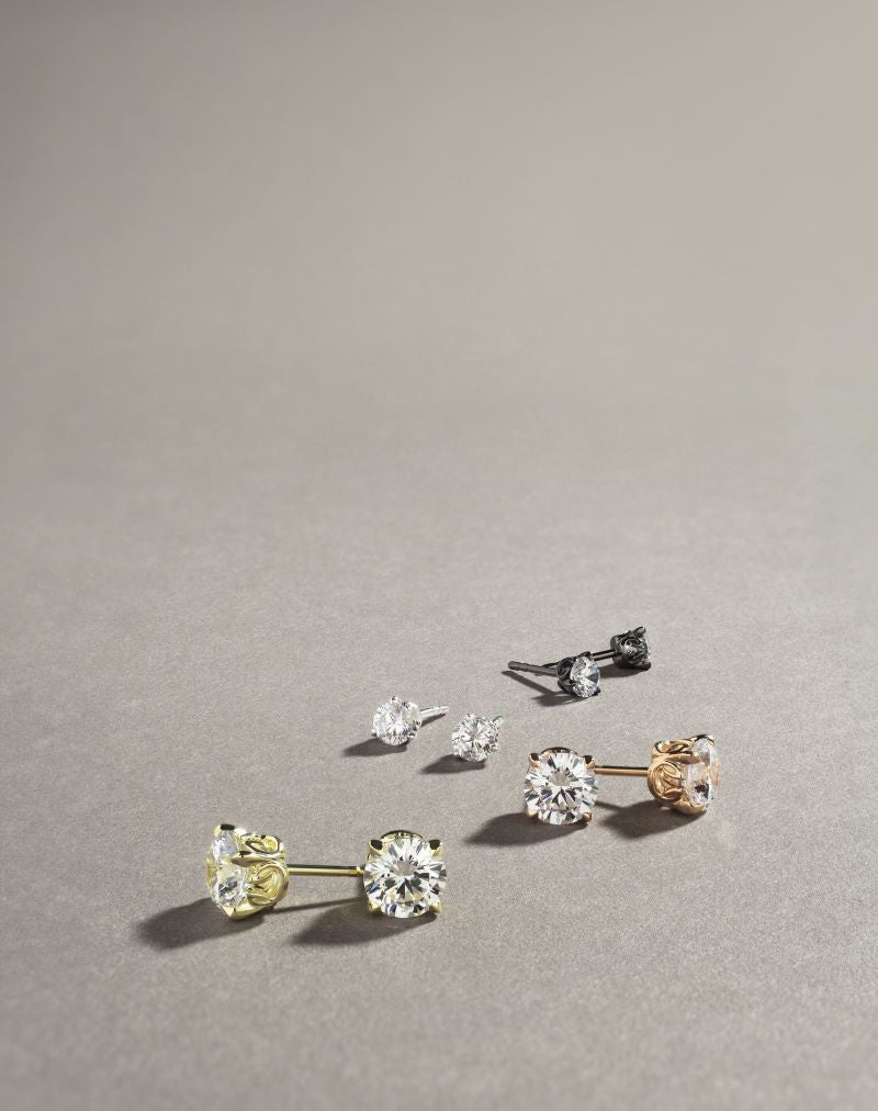 Lineup of Solitaire Stud Earrings in white cz with gold, black ruthenium, sterling silver and rose gold