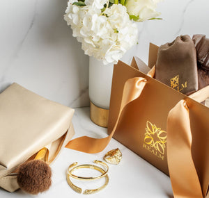 vignette of gold jewelry, makeup bag and signature gift bag from REALM
