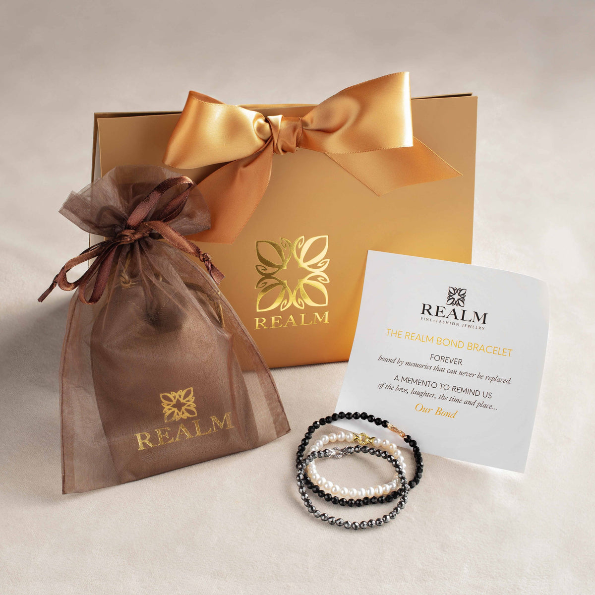 Trio of REALM Bond Bracelets with luxe gift packaging and special memento card