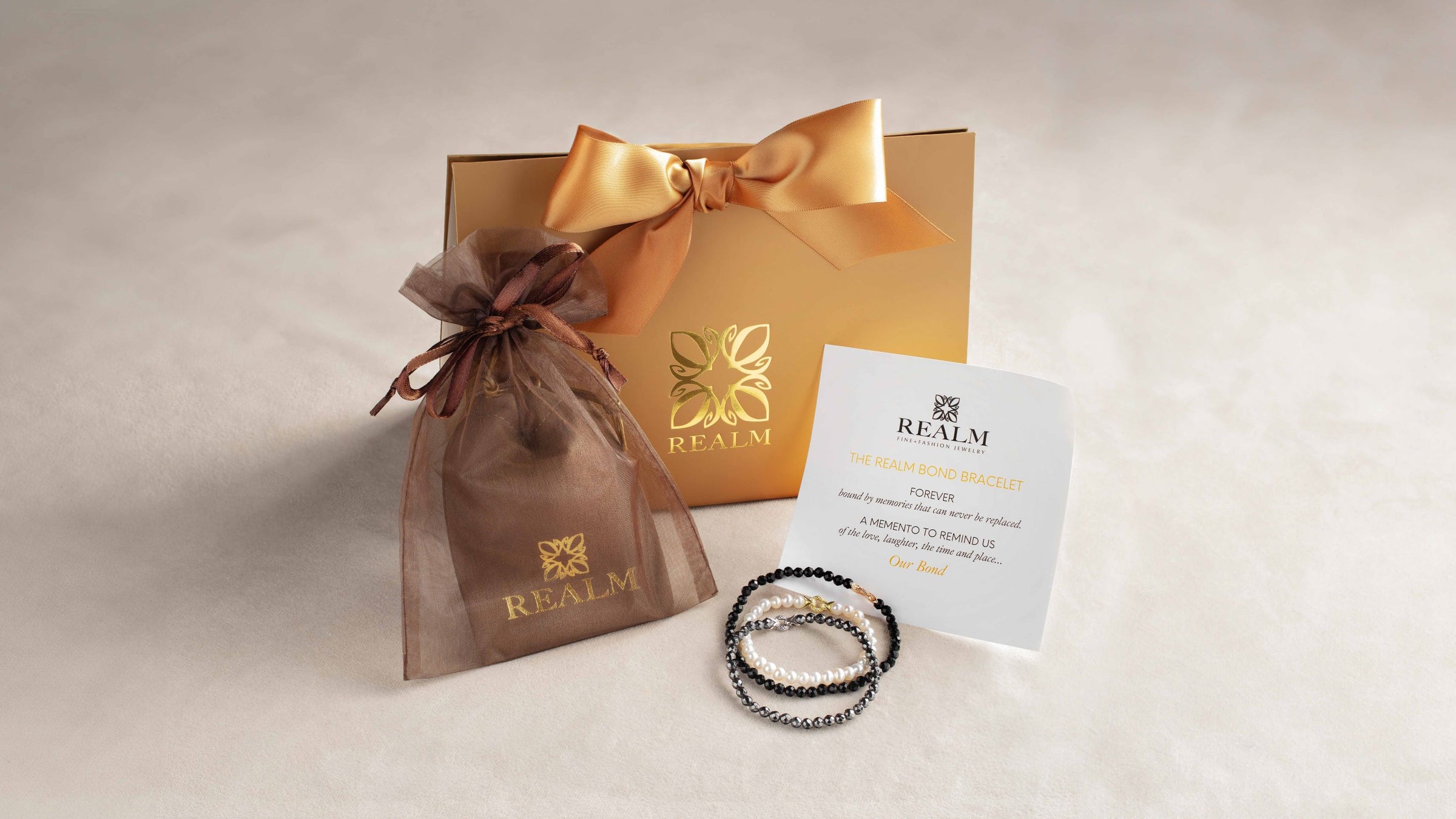Trio of REALM Bond Bracelets with luxe gift packaging and special memento card
